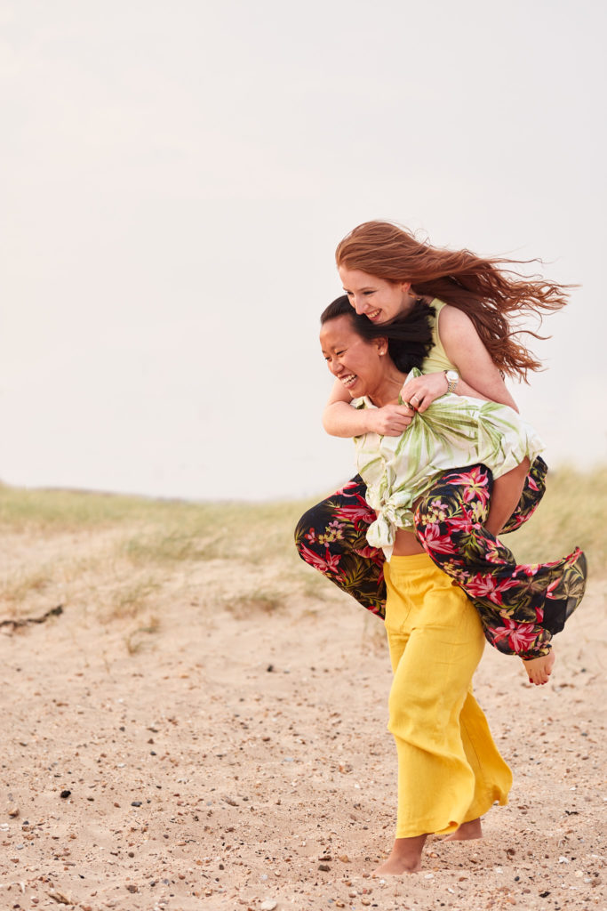 Woman giving her fiancée a piggyback on the sand