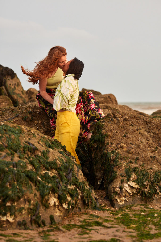 Two women kissing among the rocks on the beach