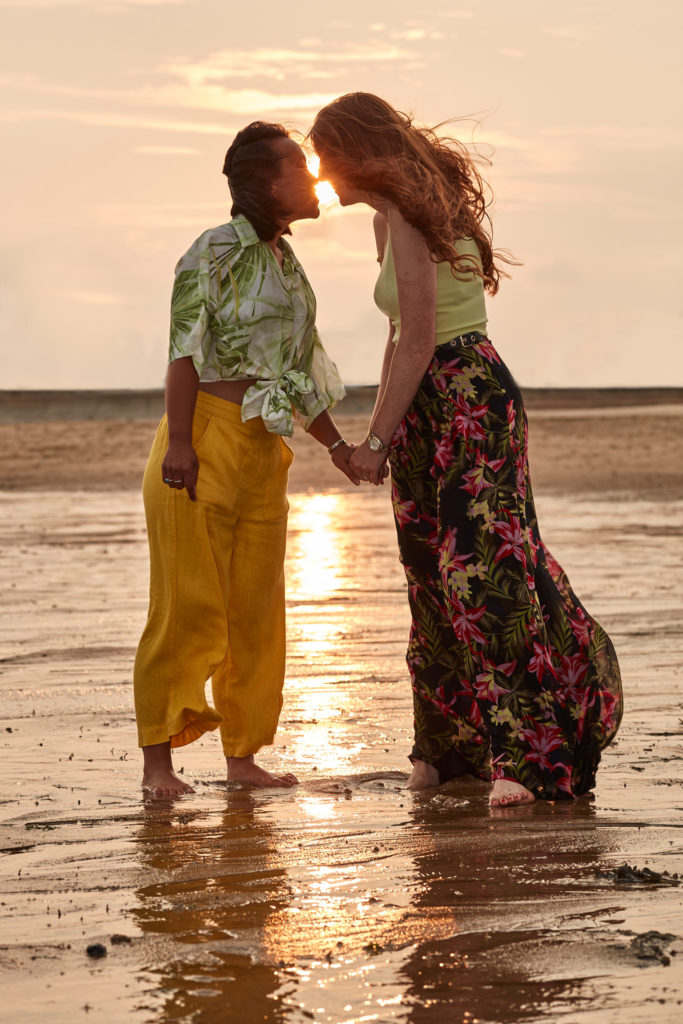 Engaged couple forehead to forehead at the water's edge at sunset on Clacton beach