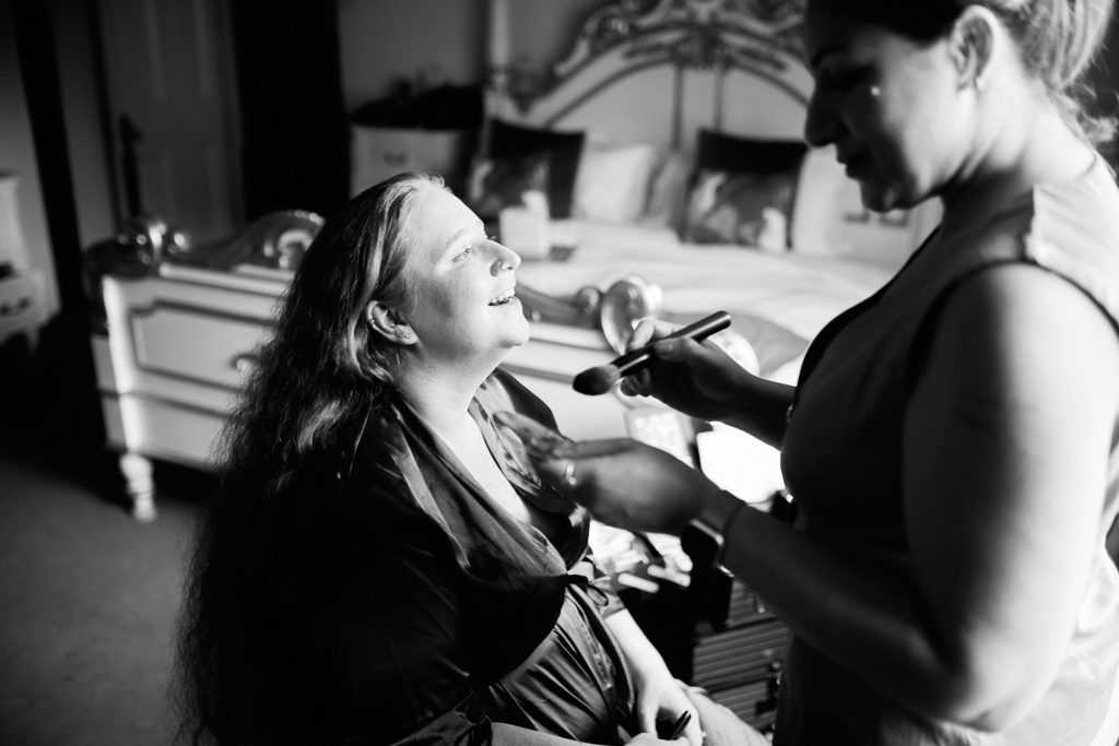 Black and white photo of the bride having her make-up applied