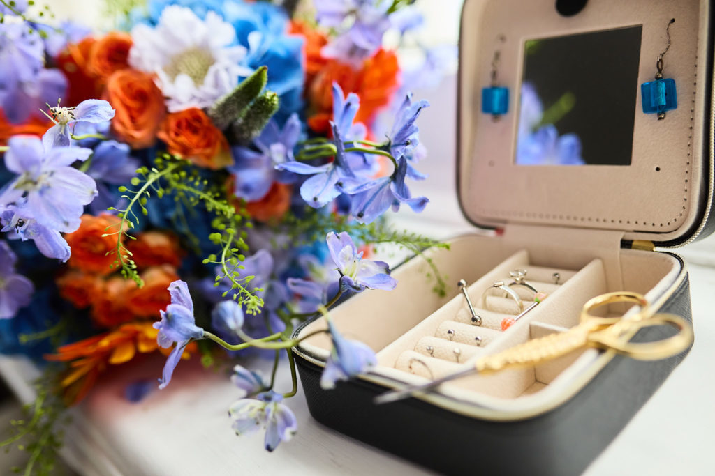 Open jewellery box beside the blue and orange bridal bouquet