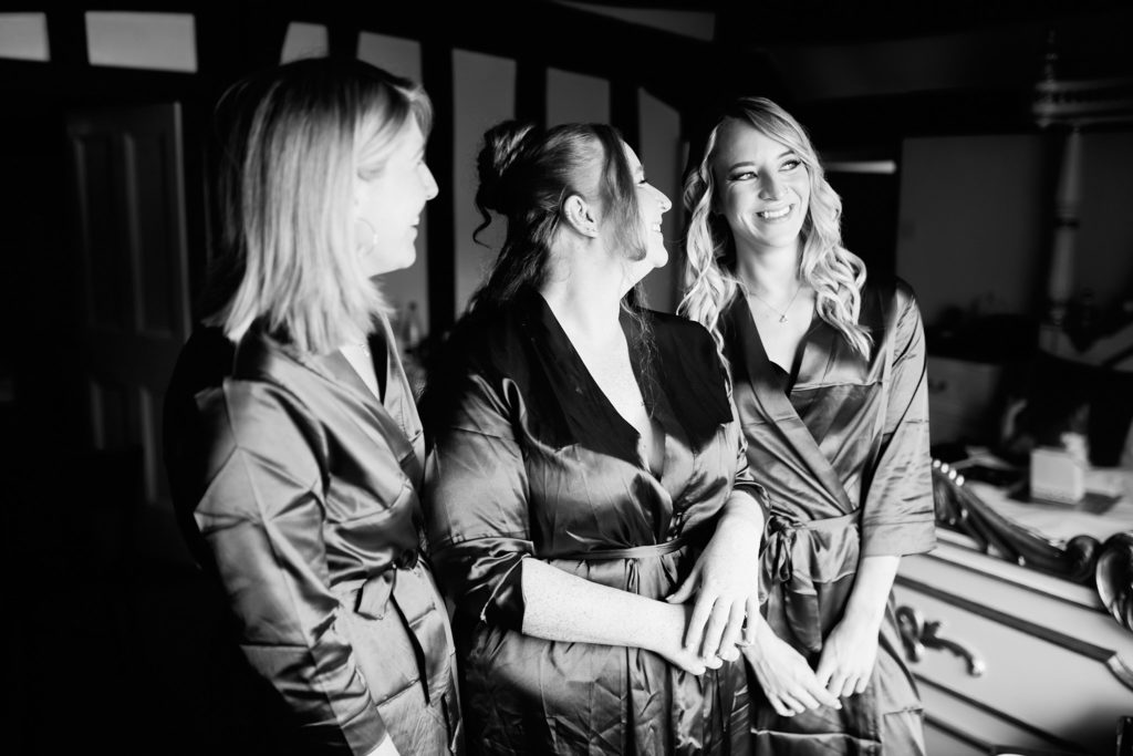 Black and white photo of the bride and two bridesmaids chatting in satin robes