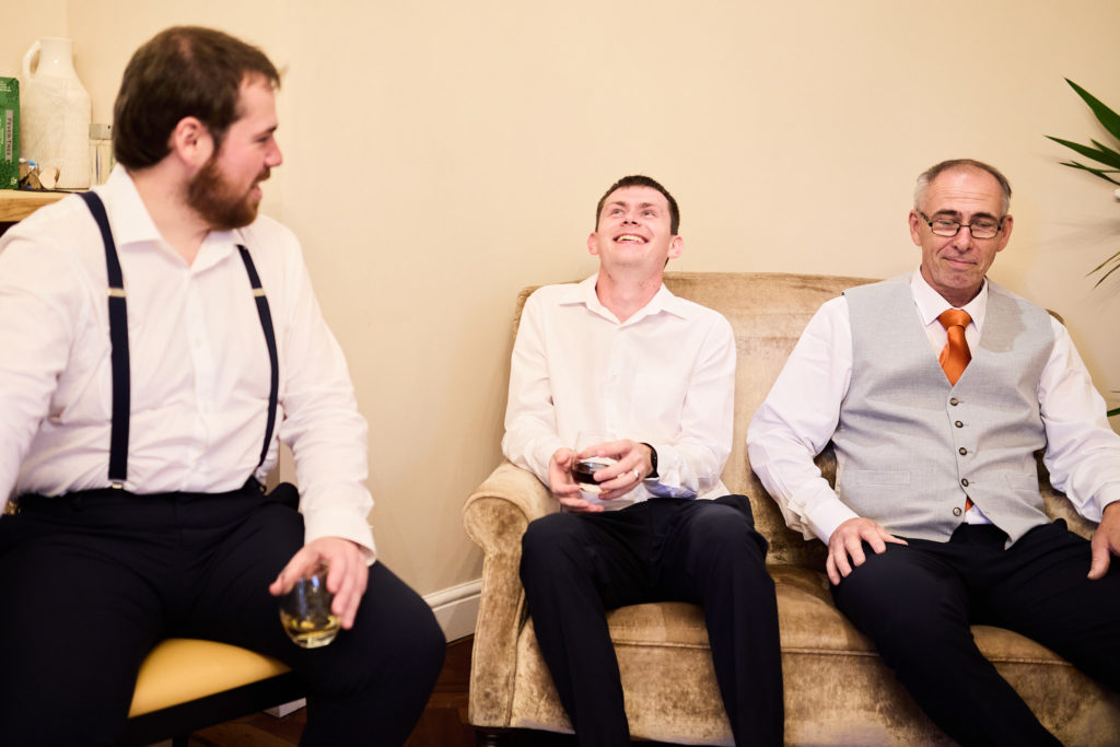 Groom in braces laughing with his groomsmen as they get ready