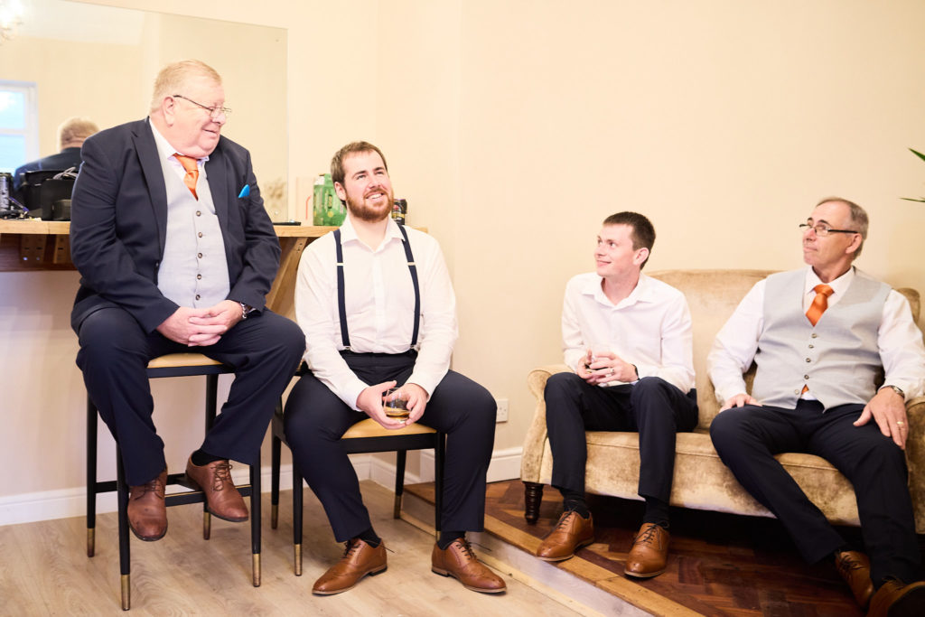 Groom and groomsmen sitting together and laughing before the wedding