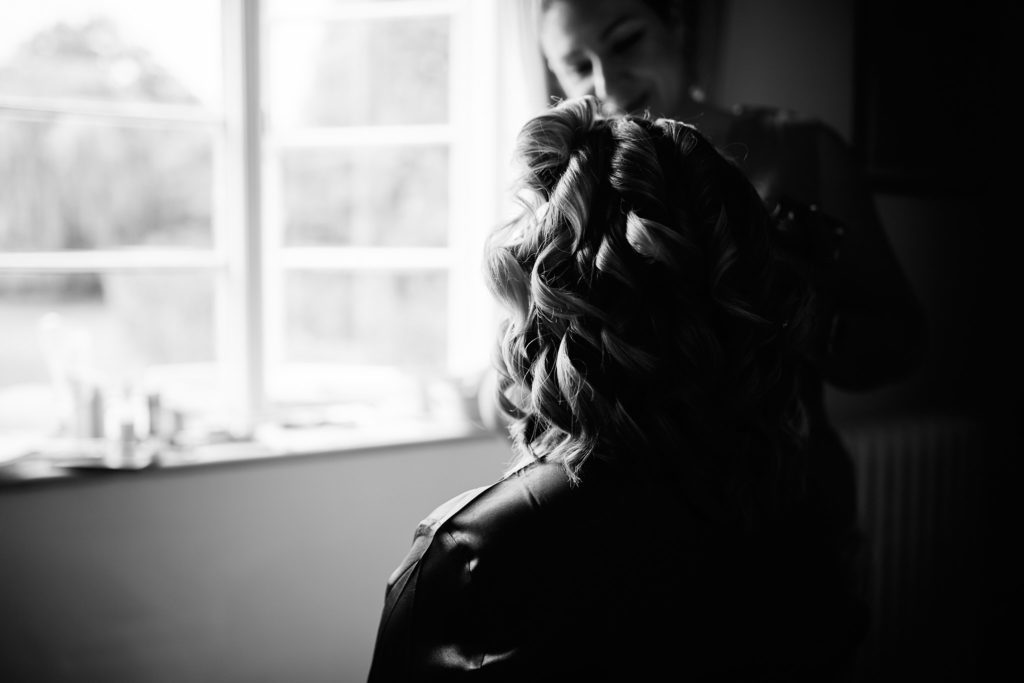 Black and white photo of the bride's curled hair in silhouette by a window