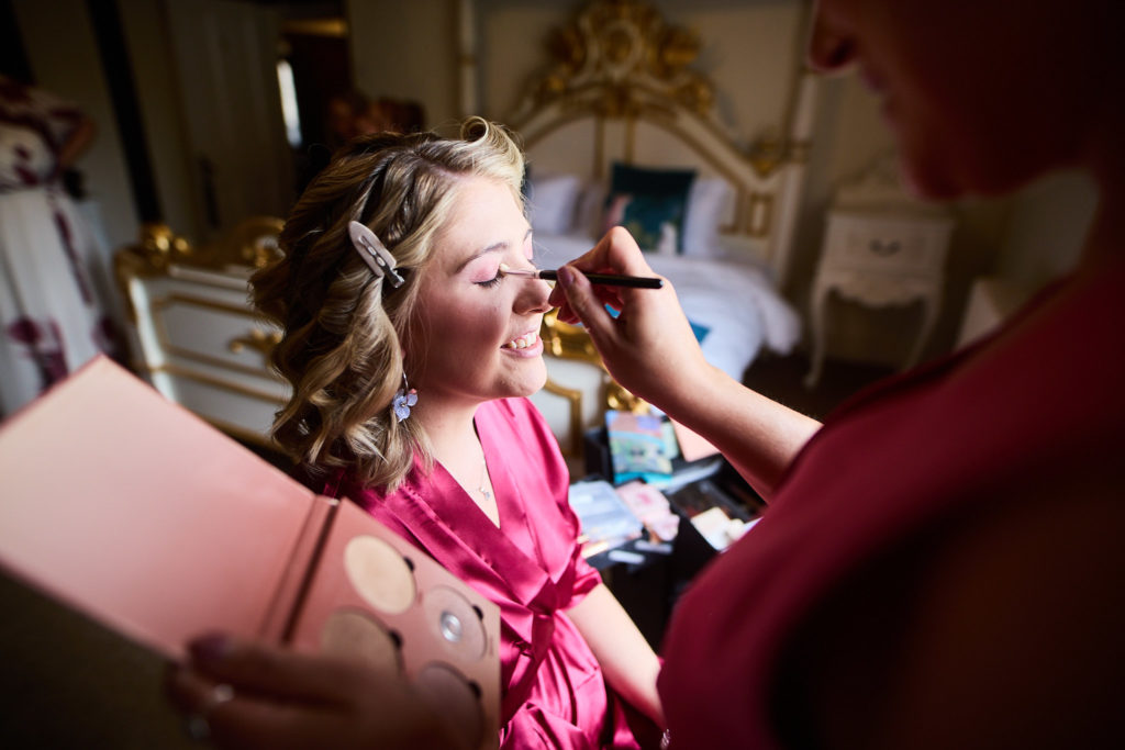 Bride with curled hair having her make-up applied
