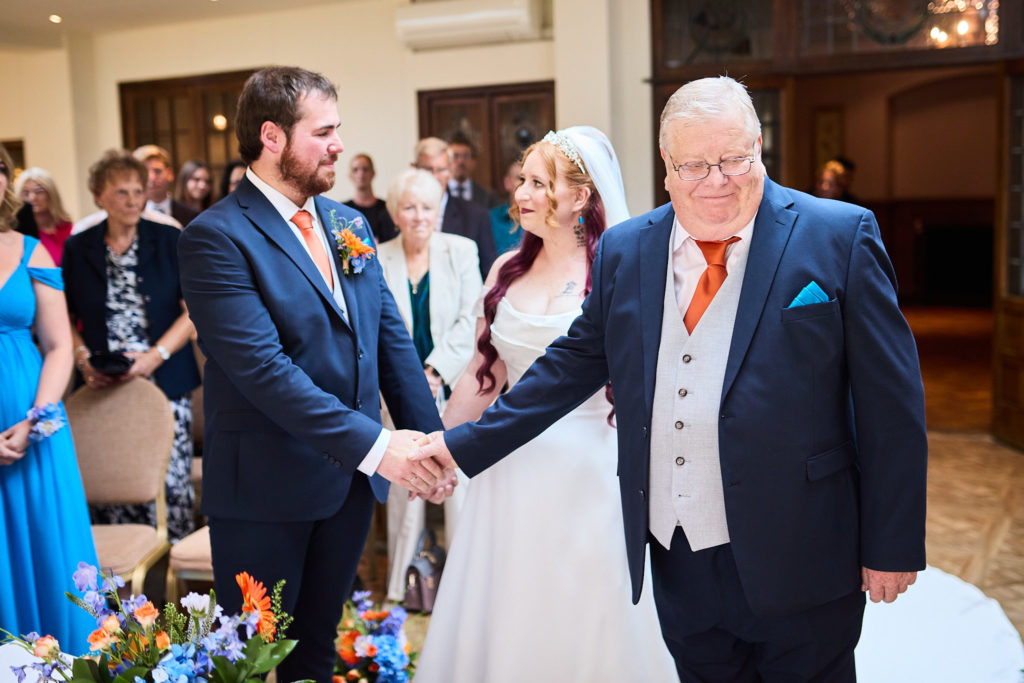 Groom shaking hands with the father of the bride after he walks her down the aisle