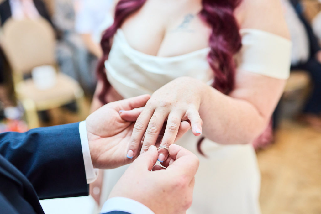 Close-up of the wedding ring being placed on the bride's finger