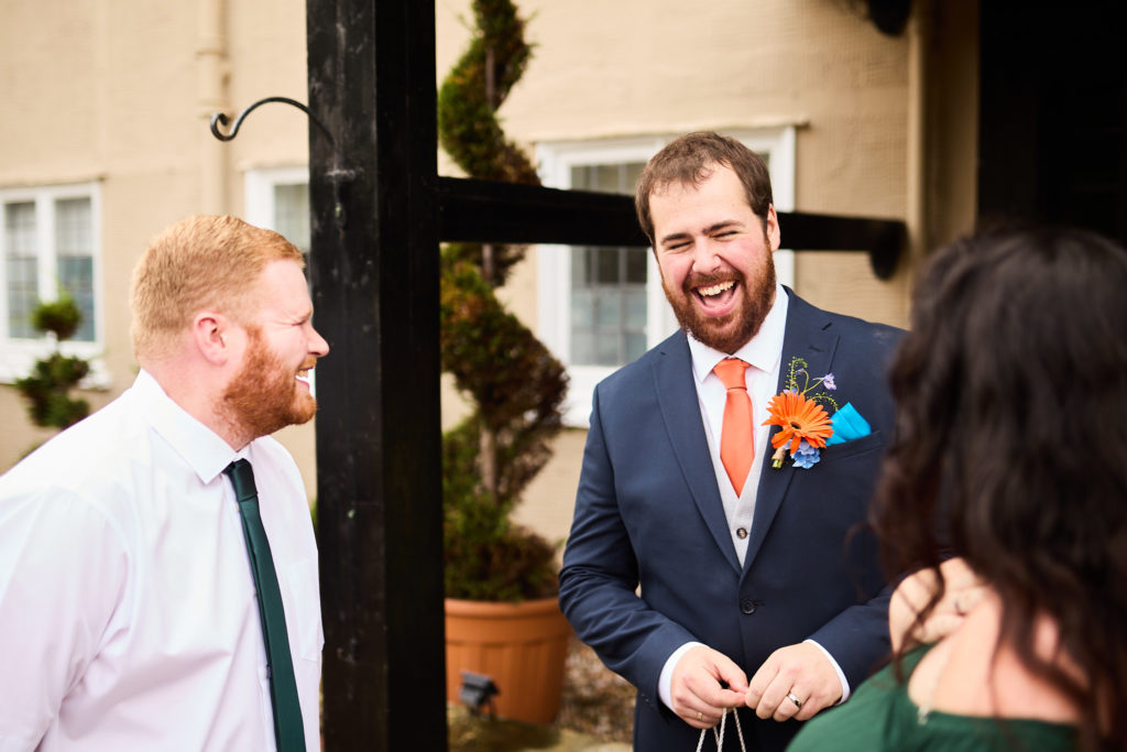 Groom laughing with guests outside after the ceremony
