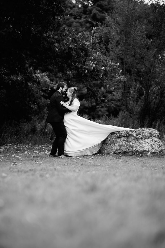 Black and white photo of the groom dipping the bride as her dress billows, Prested Hall wedding
