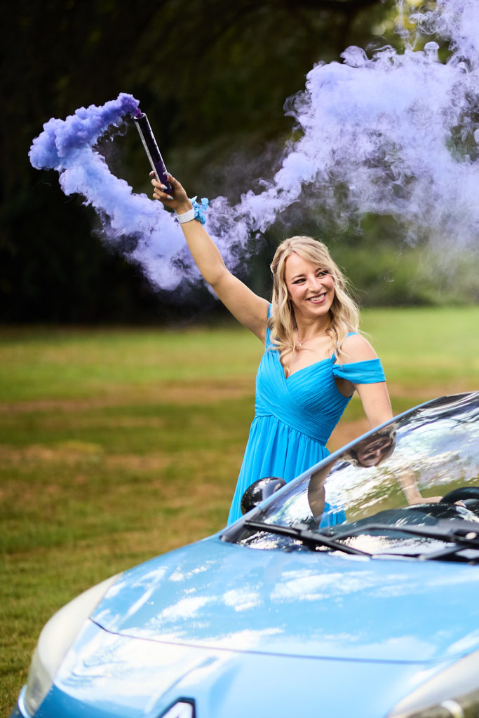 Bridesmaid in a blue dress holding a purple smoke flare in the air