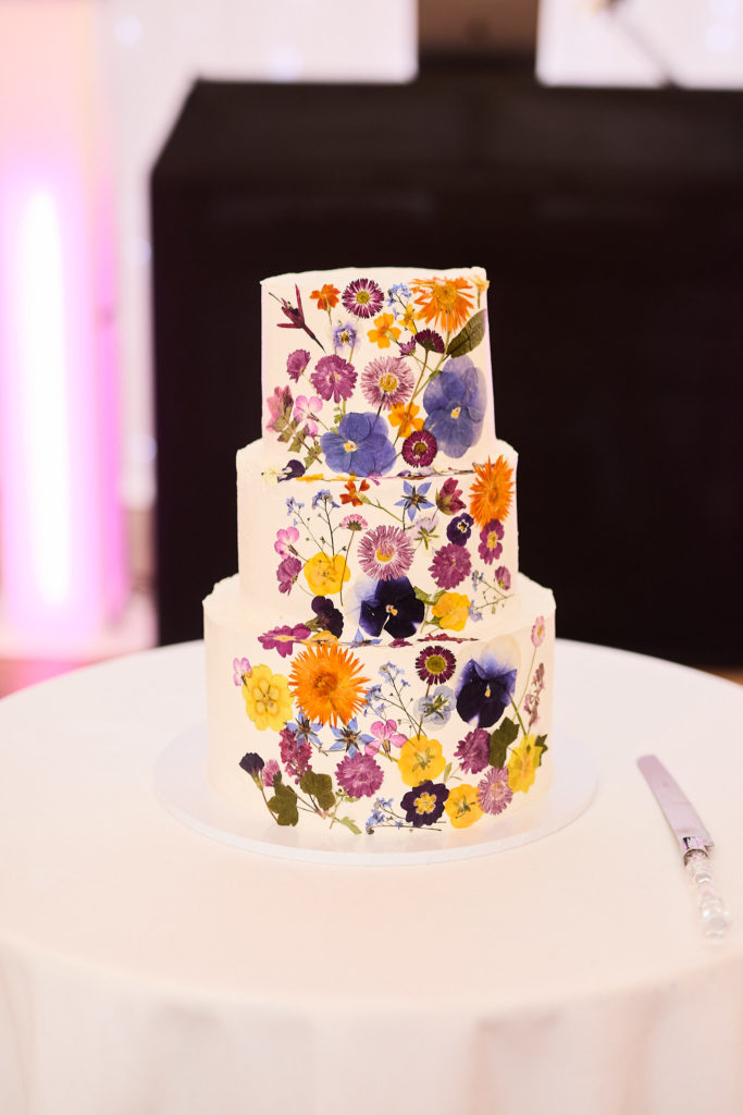 Three-tier wedding cake decorated with pressed flowers