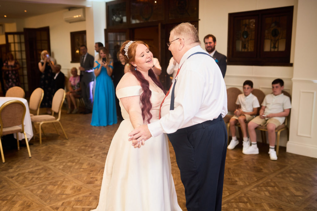 Bride dancing with her father as guests watch