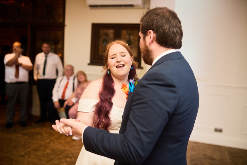 Bride laughing as she dances with the groom