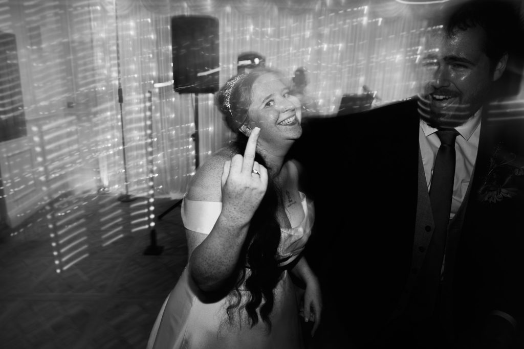 Black and white photo of a guest pulling a face at the camera on the dance floor