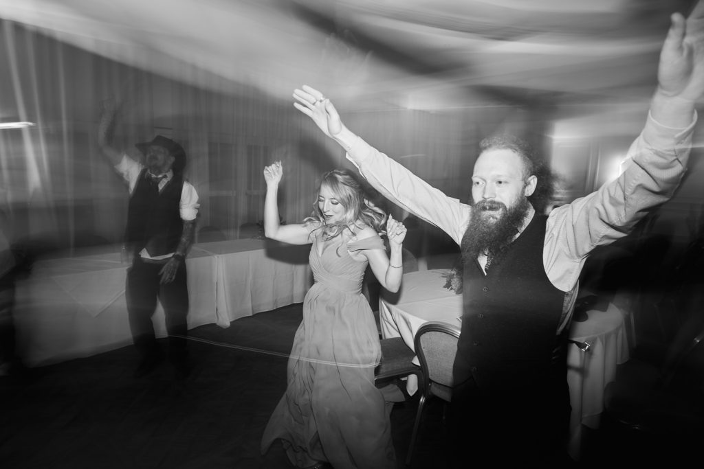 Black and white photo of a bearded guest dancing with his arms in the air