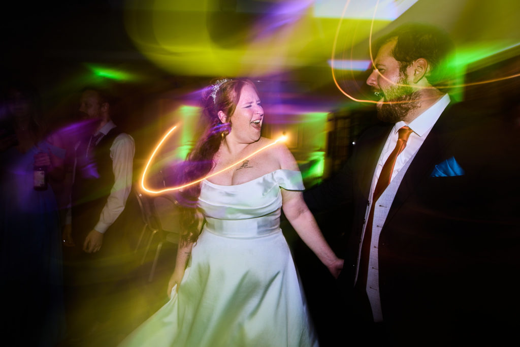 Bride and groom dancing among colourful light trails