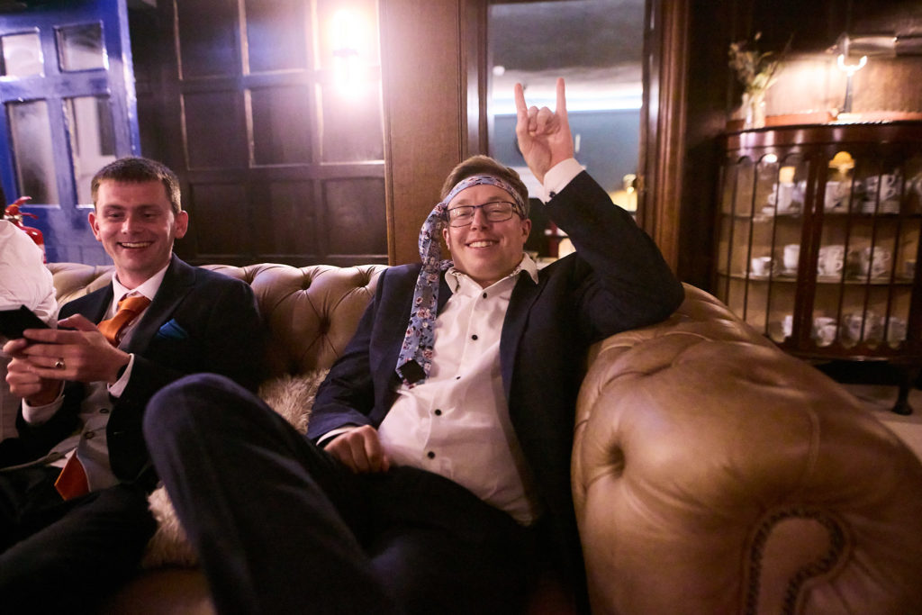 Wedding guests relaxing on a leather sofa in the evening