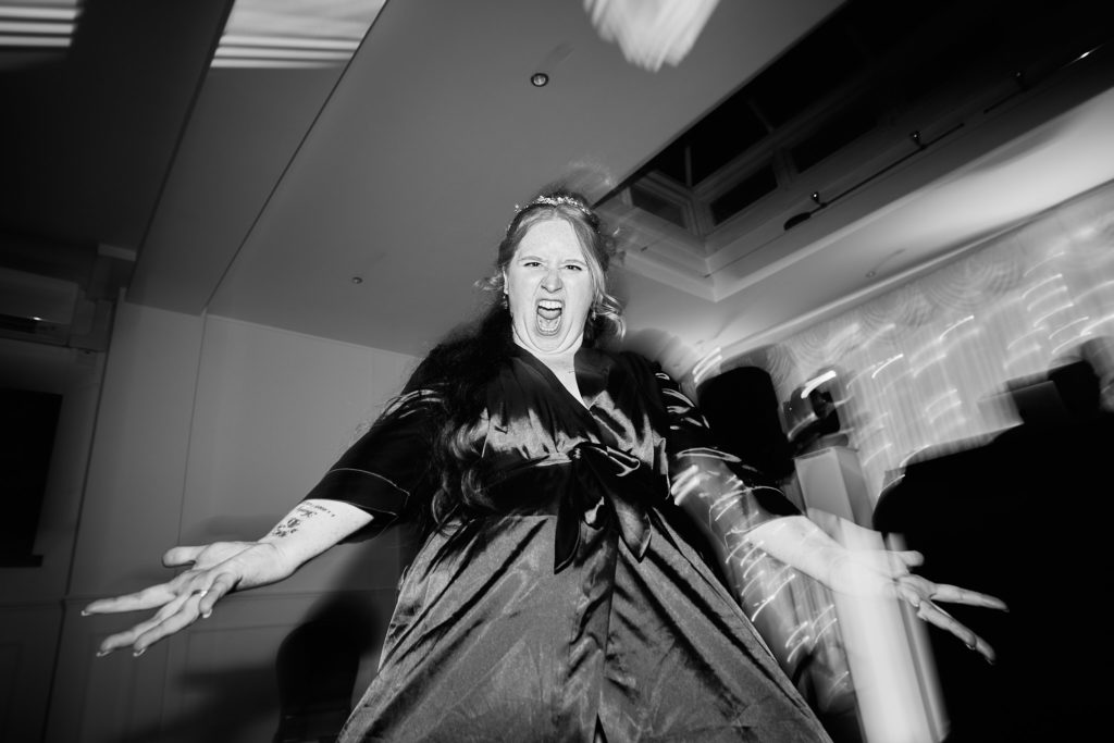 Black and white photo of a guest dancing with her arms flung wide