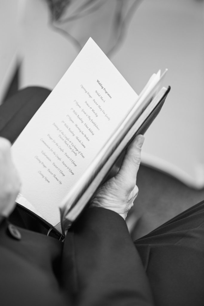 Black and white close-up of a guest holding the order of service