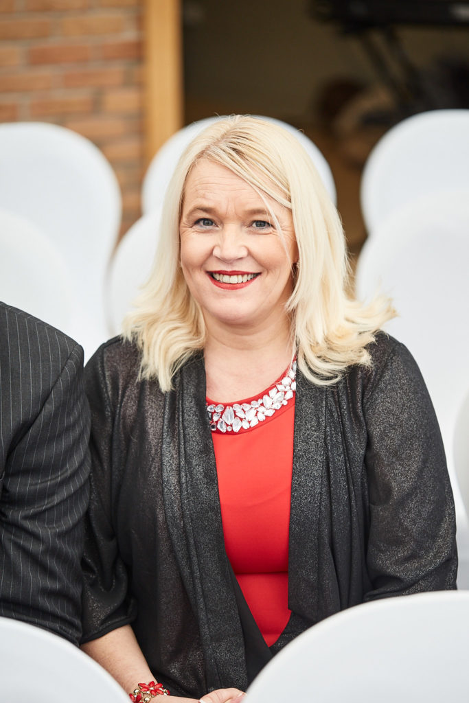 Wedding guest in a red dress smiling in her seat