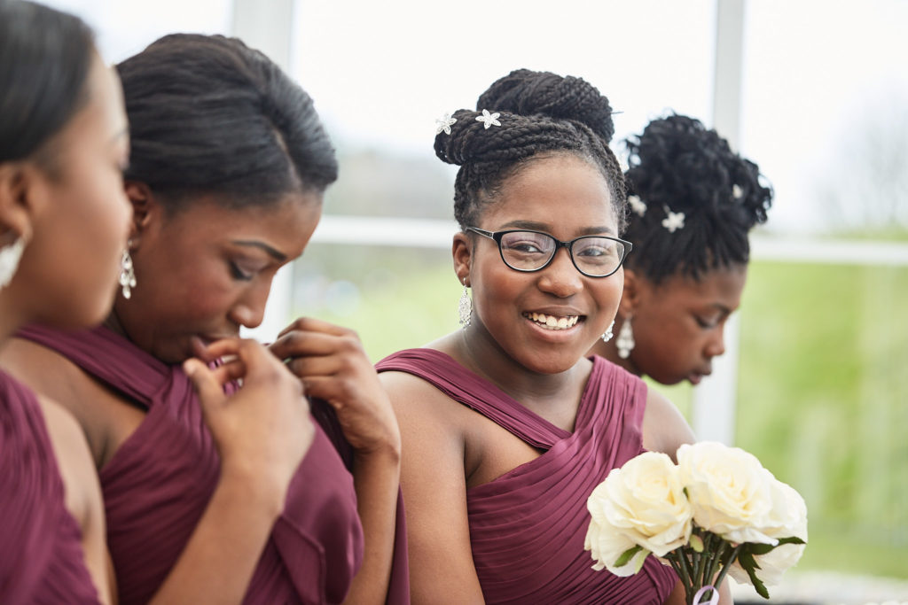 Bridesmaids in burgundy dresses laughing together during the ceremony