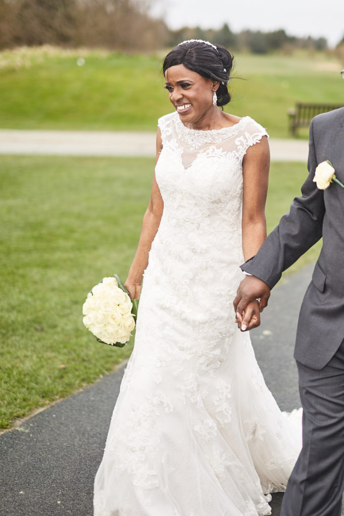 Bride laughing as she walks hand in hand with the groom across the golf course at Essex Golf Club