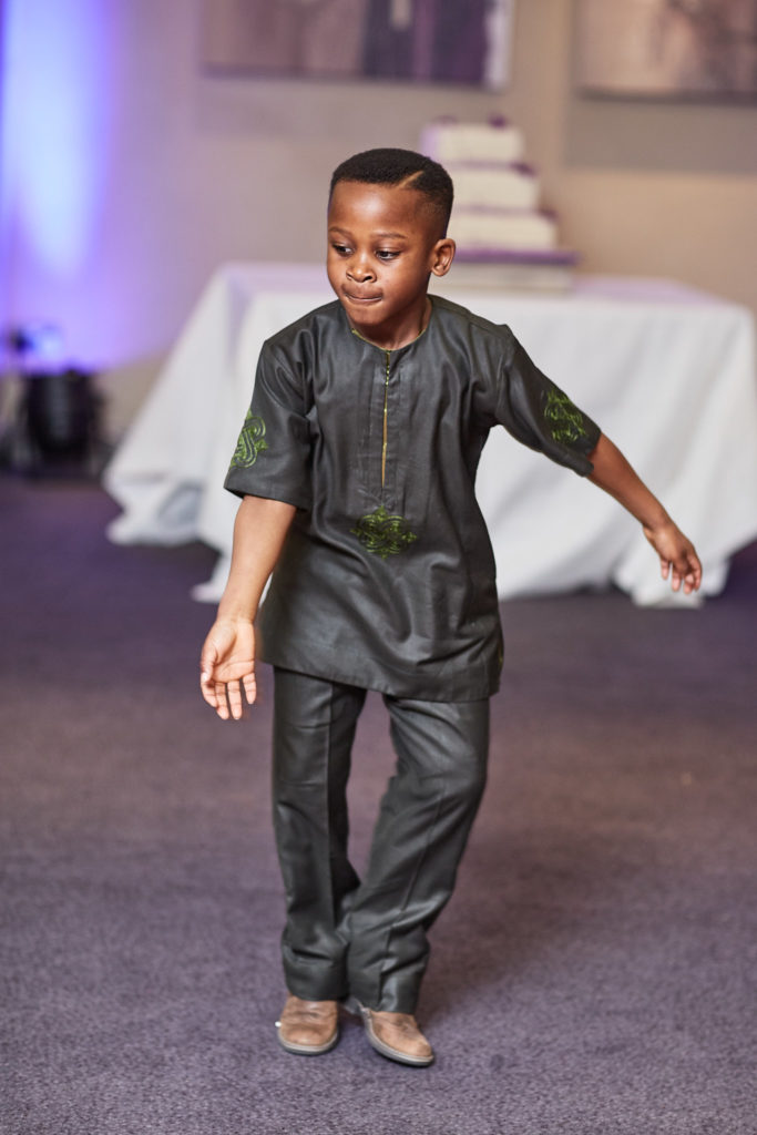 Young boy in a grey suit dancing on the dance floor