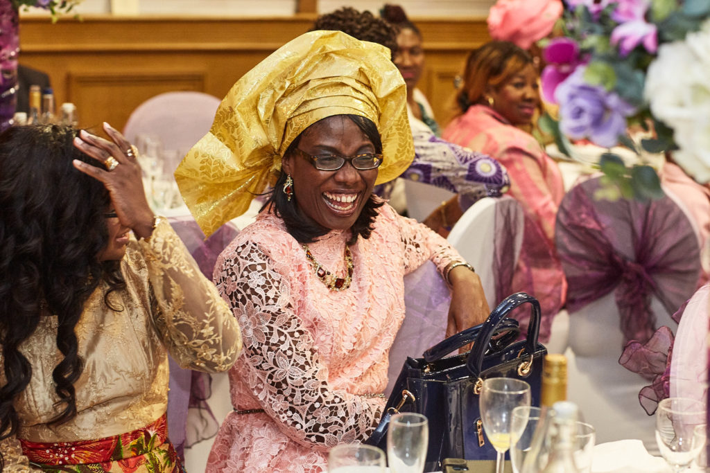 Guests in gold and pink head ties laughing at their table