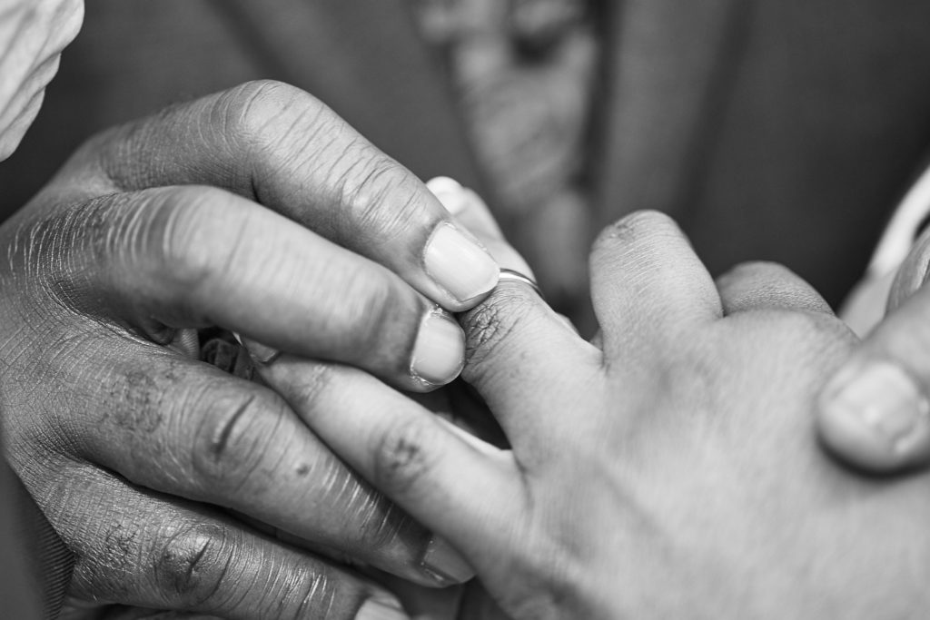 Black and white close-up of the bride and groom's hands during the exchange of rings