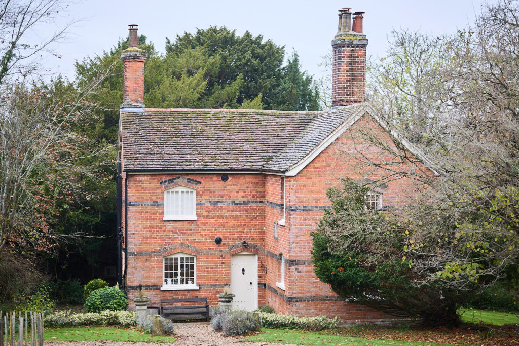 Red-brick cottage among the trees at Hedingham Castle