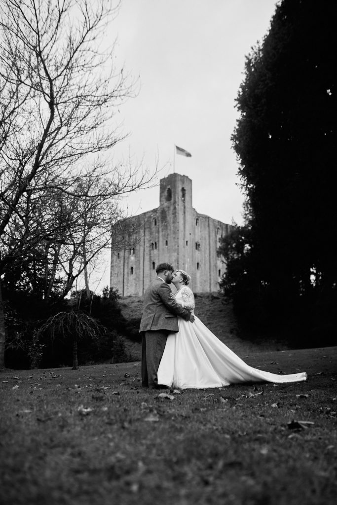 Black and white photo of the bride and groom in front of the keep at Hedingham Castle