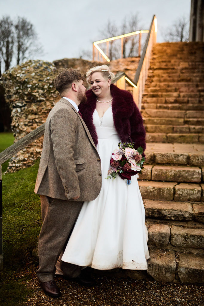 Bride and groom at the foot of the stone steps at Hedingham Castle