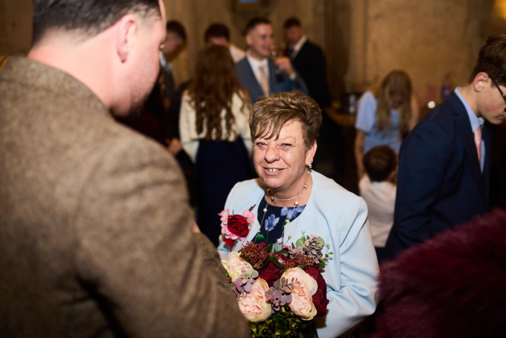 Wedding guest laughing as she holds a bouquet of roses