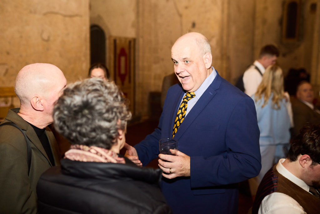 Older guest in a navy suit chatting with other guests