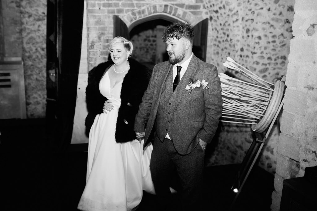 Black and white photo of the bride and groom entering the hall hand in hand