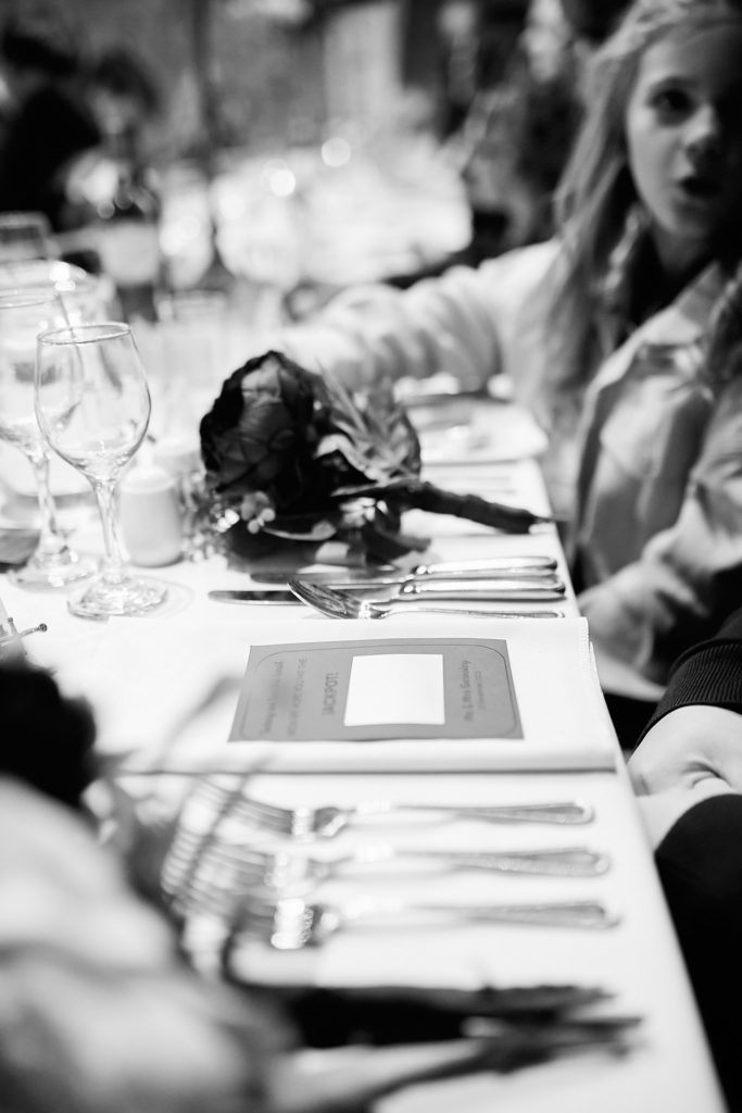 Black and white photo of a place setting with a guest in the background