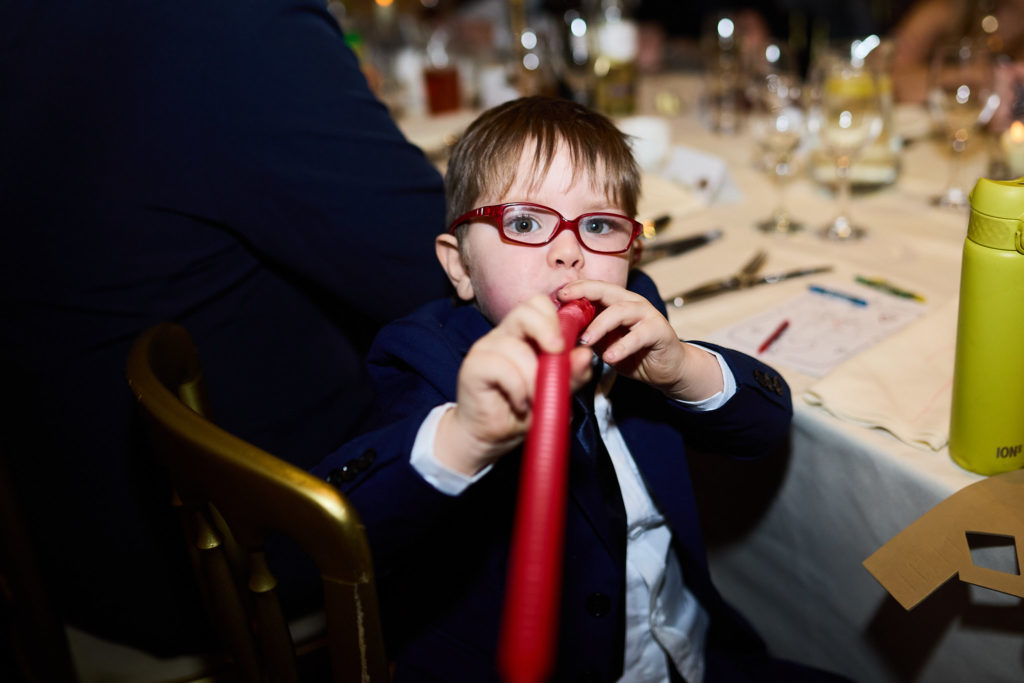 Boy in red glasses playing with a red balloon at the table