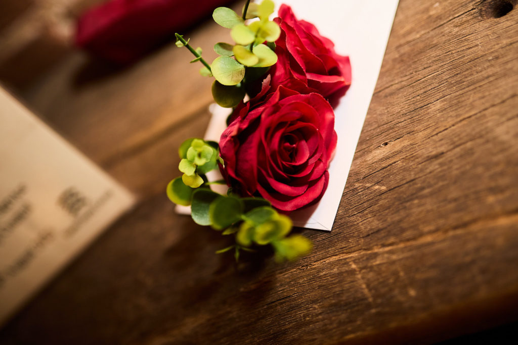 Red rose buttonhole on a wooden table