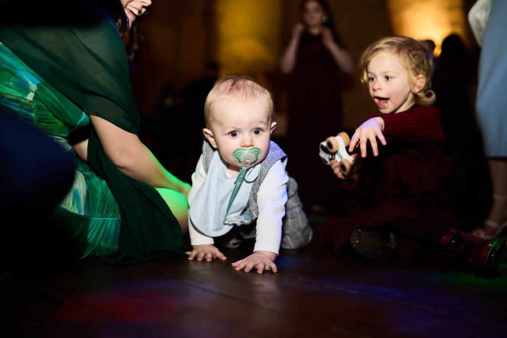 Baby crawling across the dance floor with a toddler behind