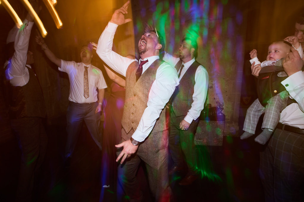 Man in a waistcoat dancing among streaks of coloured light