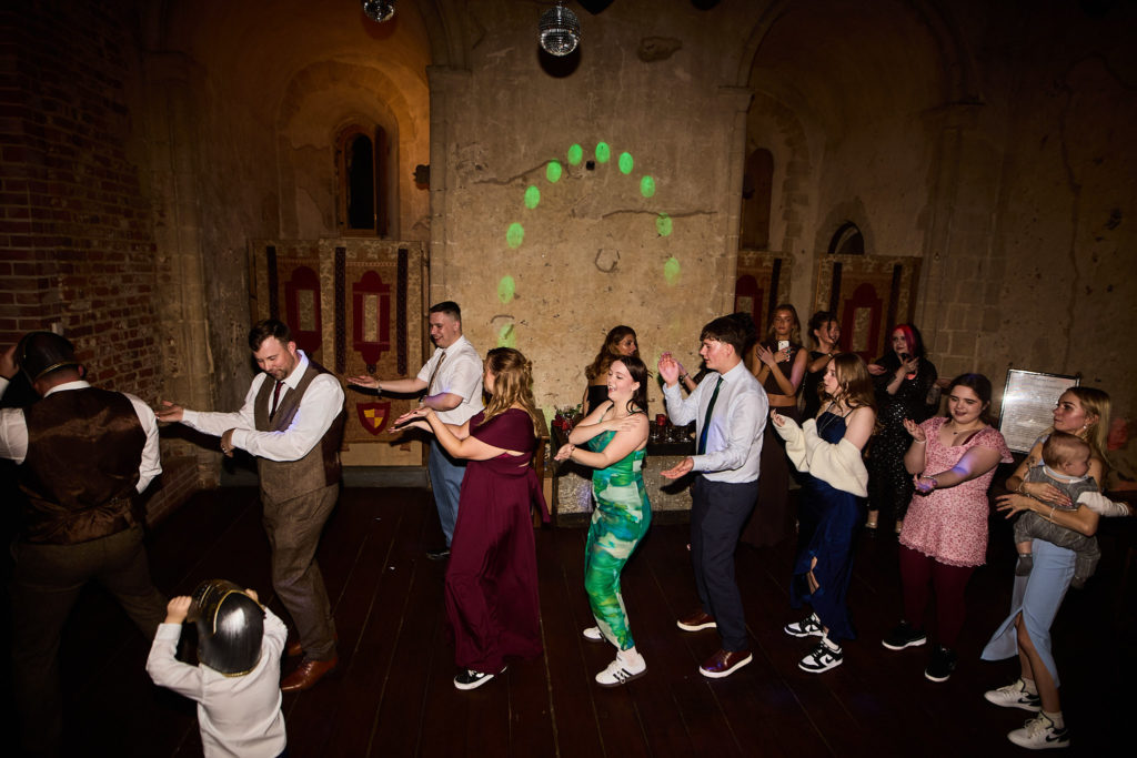 Wedding guests dancing in a line across the hall