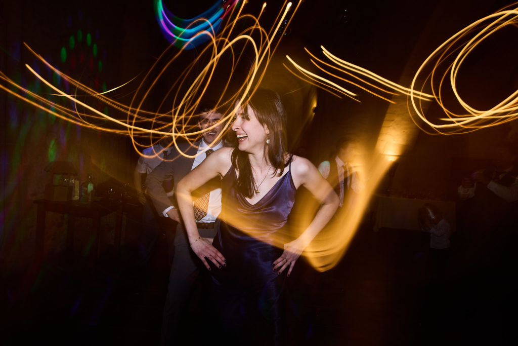 Wedding guest dancing under swirling trails of light
