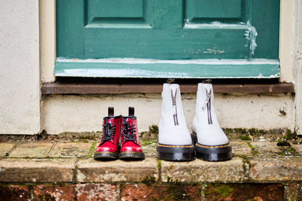 Red and white Dr Martens boots on a doorstep in front of a green door
