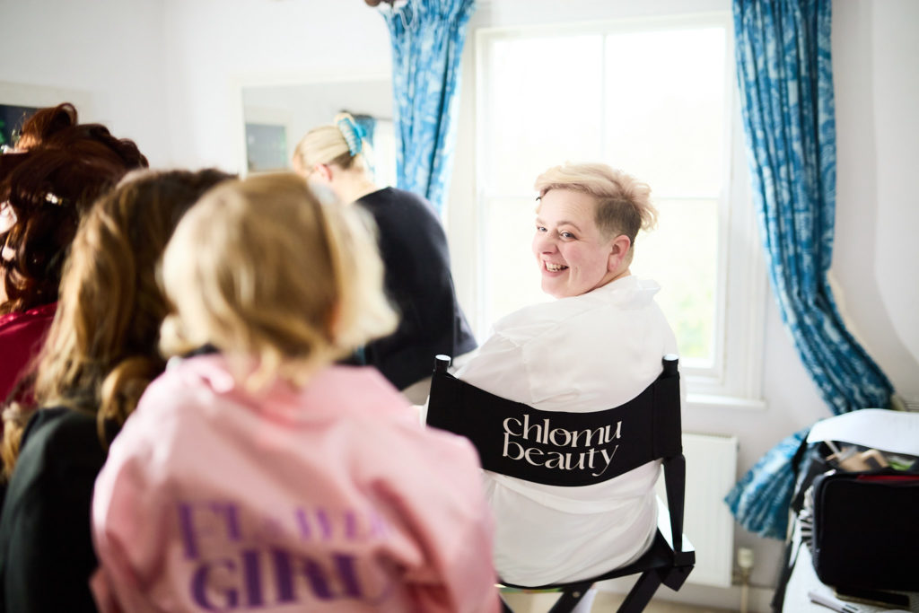 Bride in the make-up chair with her bridal party around her