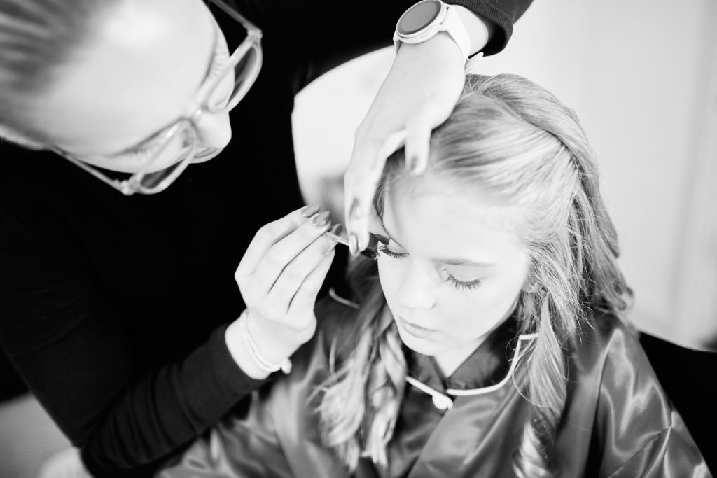 Black and white photo of a stylist curling a bridesmaid's hair