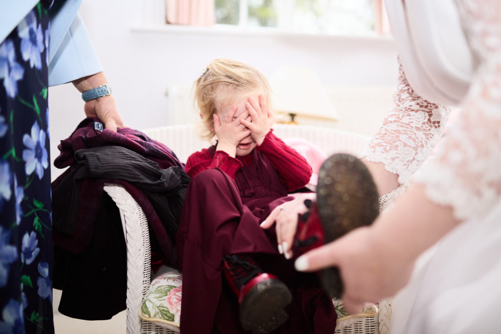 Young bridesmaid in a burgundy dress hiding her face behind her hands