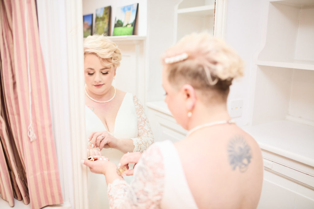 Bride having her bracelet fastened by a bridesmaid