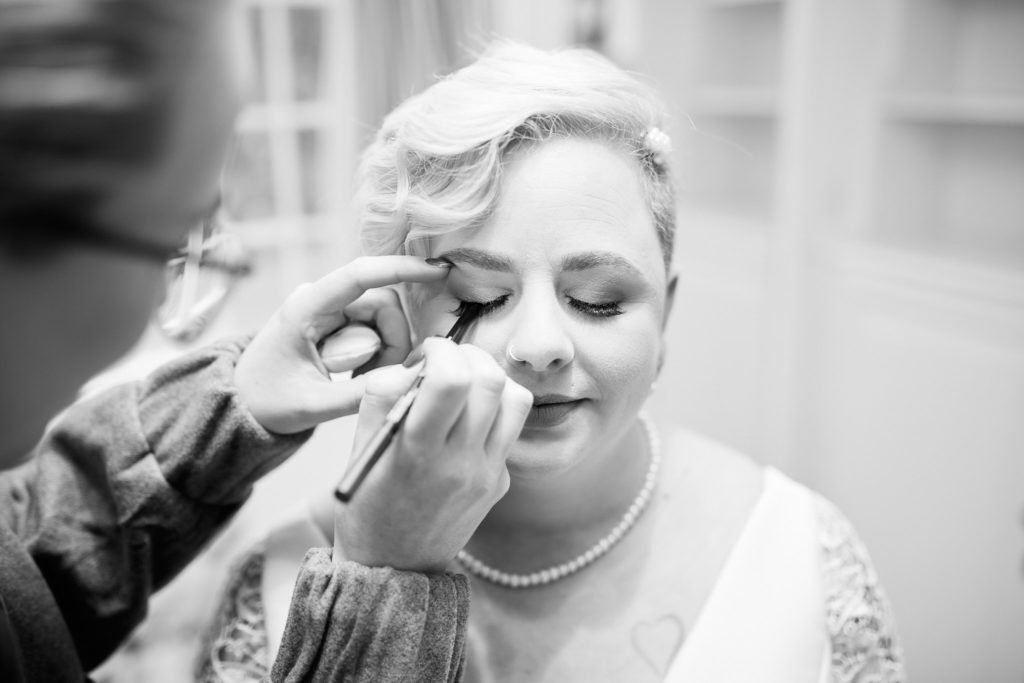 Black and white close-up of the bride having her eye make-up applied