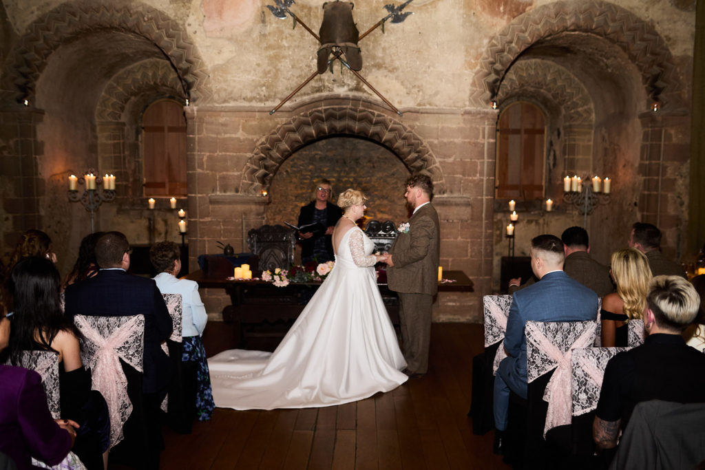 Wedding ceremony beneath the great stone arch in the banqueting hall at Hedingham Castle